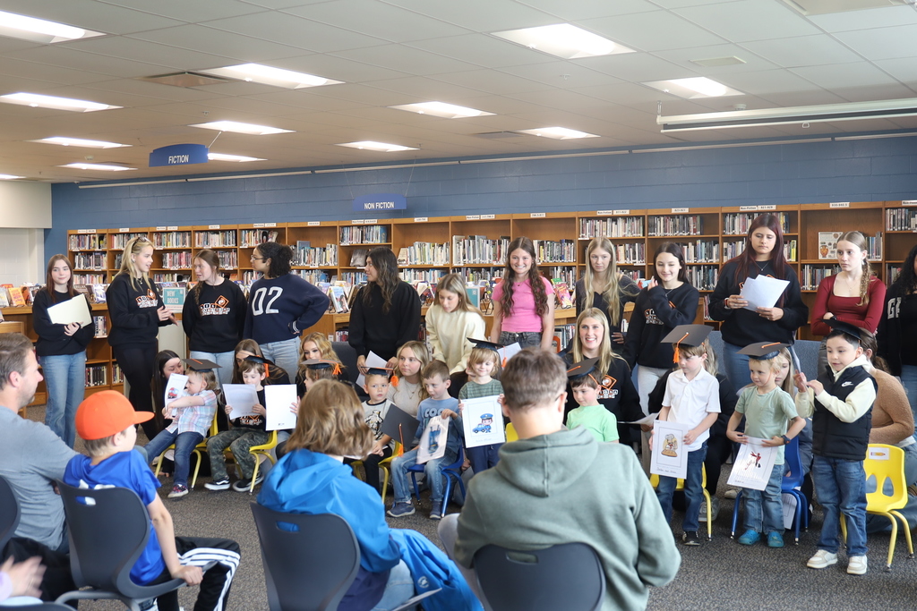 High Schoolers with preschoolers in graduation caps