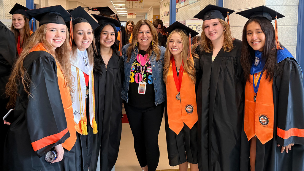 Students in caps and gowns with teacher