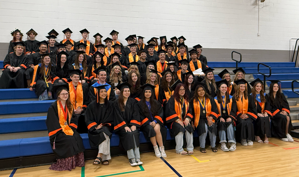 Studnets in caps and gowns on bleachers 