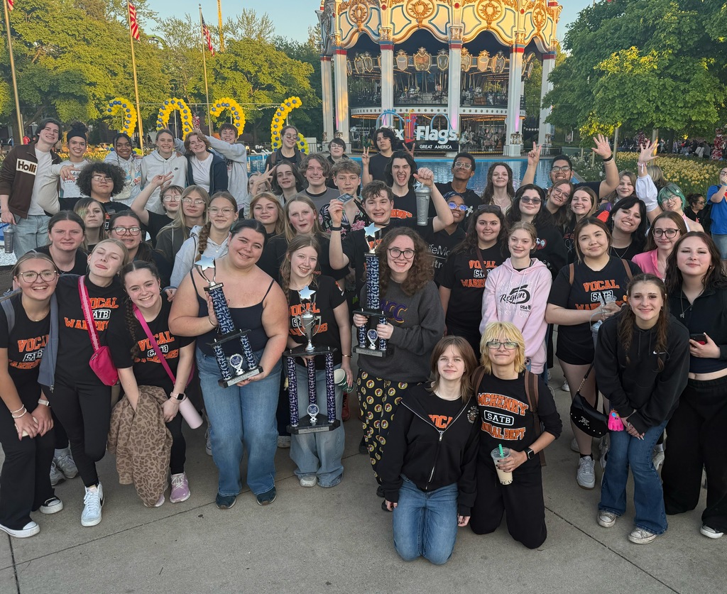 Group of choir students with three trophies in front of six flags 