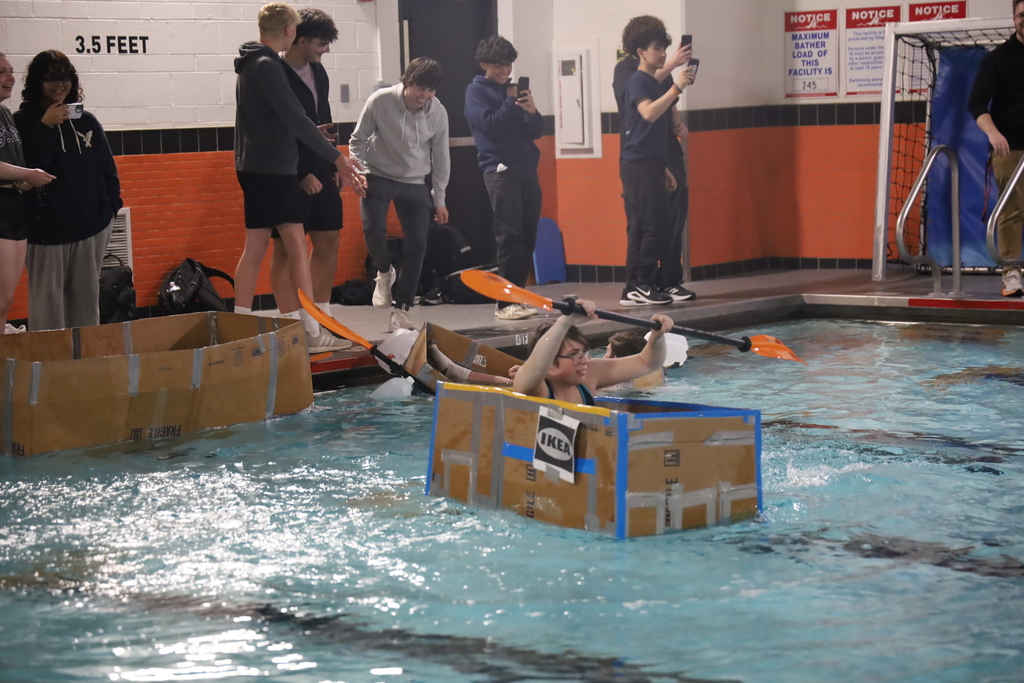 Student with kayak oar and box going across the pool