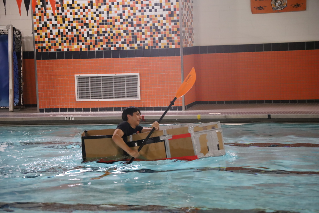 Student with kayak oar and box going across the pool