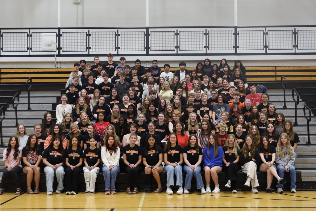 Over 140 students sitting in the bleachers posing
