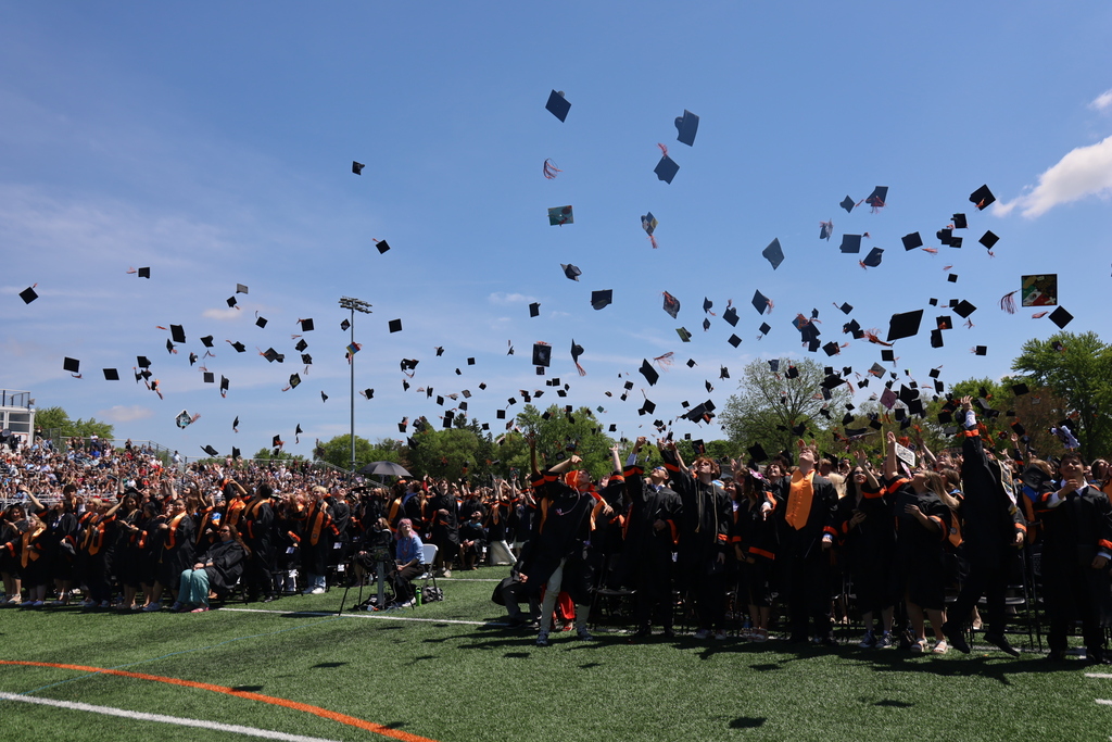 Graduates throwing grad caps in air on football field