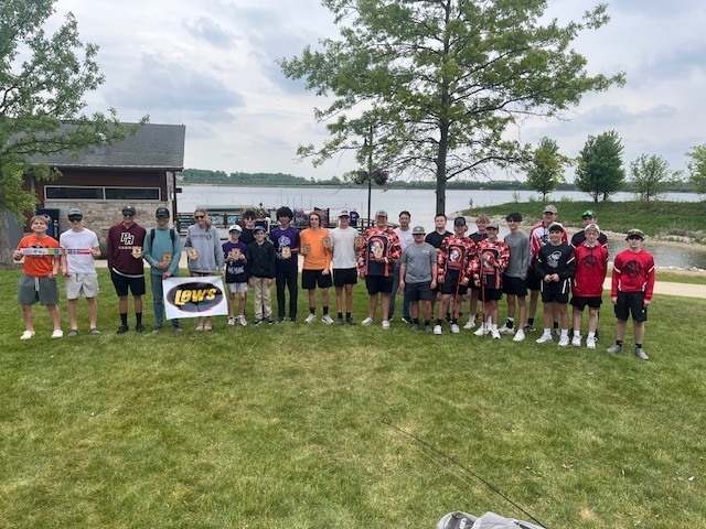 Over twenty students standing in front of lake with a Lews sign