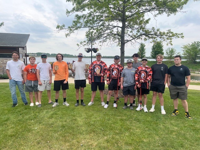 Twelve students by the lake. Two holding trophies