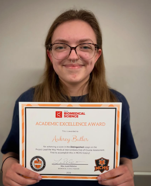 PLTW Biomedical Science. Academic Excellence Award. This is awarded to Aubrey Butler for achieving a score in the Distinguished range on the Project Lead the Way Medical Interventions End-of-Course Assessment.  First to accomplish this in MCHS history. Signed by Mrs. Leah Pelletier Biomedical Science teacher 2026. Aubery holding certificate