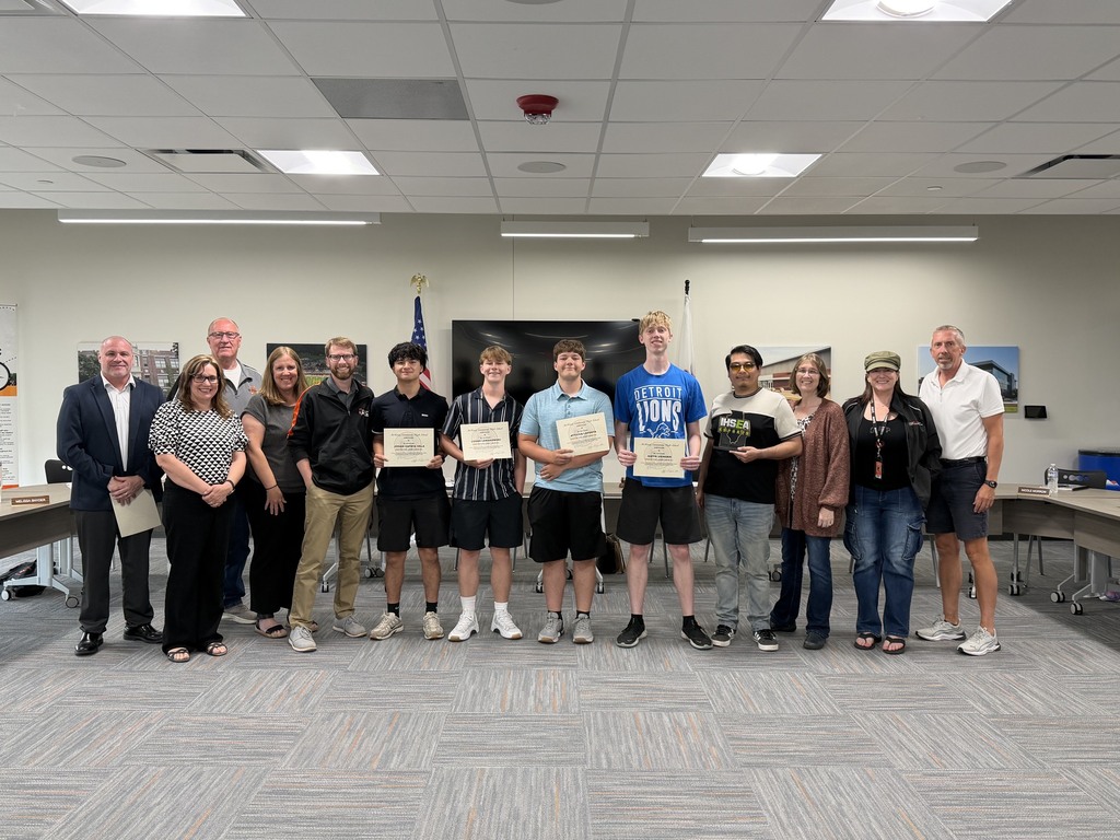 Board members and superintendent with eSports members and coach at board meeting. eSports members holding certificates