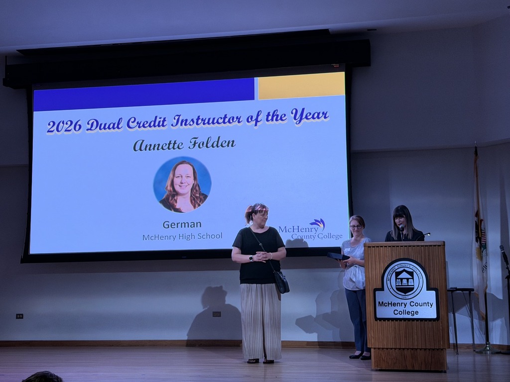 Annette Folden holding award in front of slide that says 2026 Dual Credit Instructor of the Year German McHenry County College. MCC staff presenting her the award