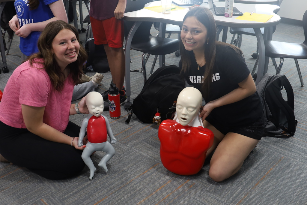 Two students with a baby CPR mannequin and adult mannequin 