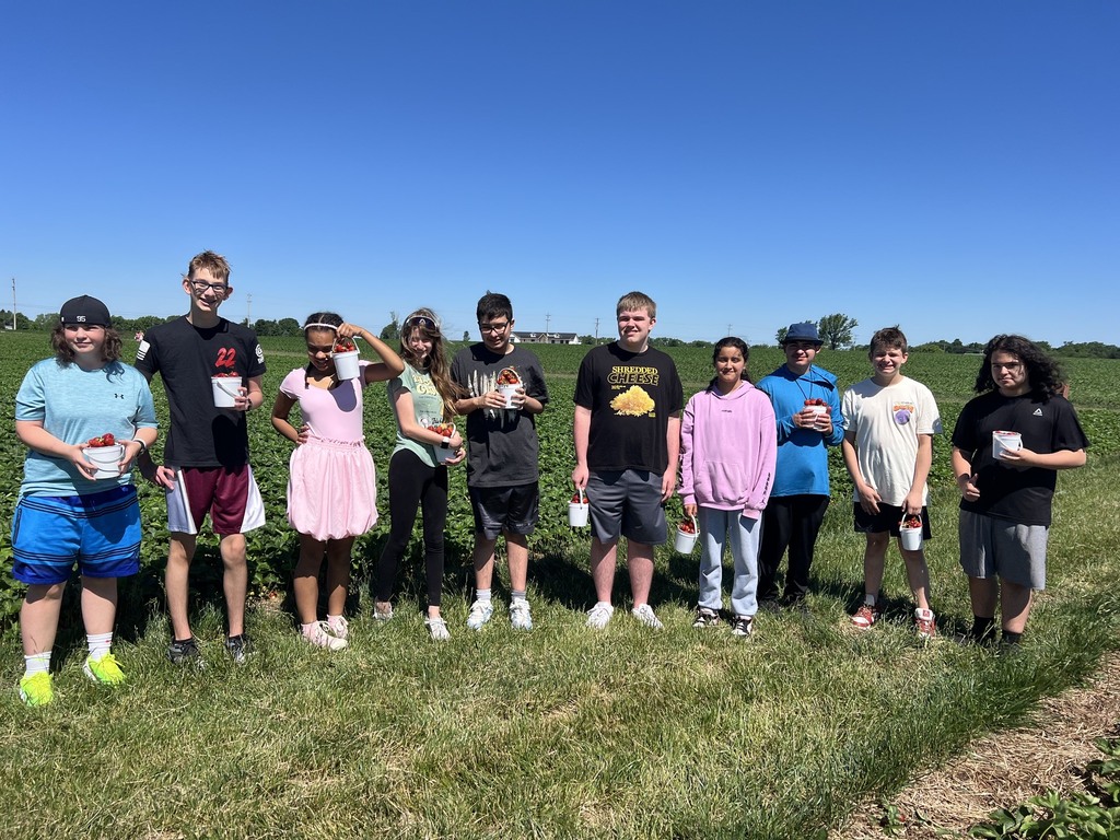Ten students in the posing in the field with pales of strawberries in their hands