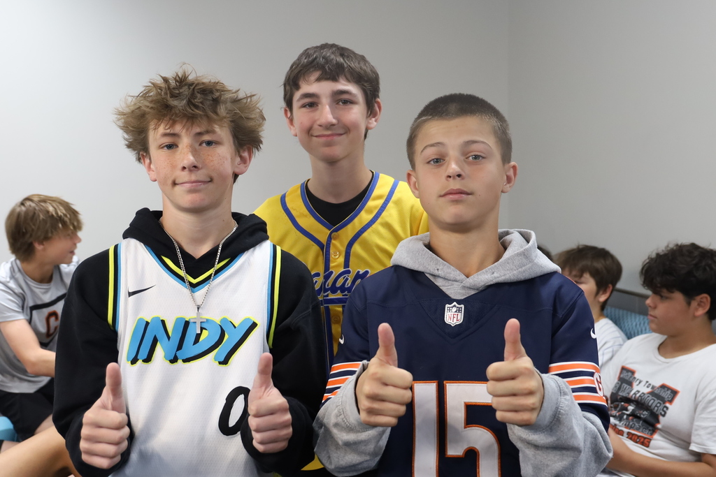 Three studnets in jerseys giving thumbs up 