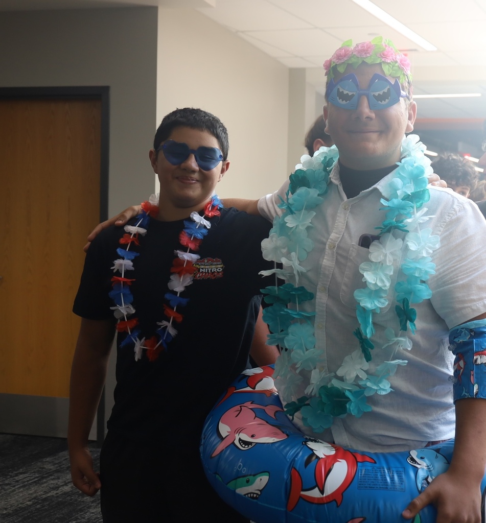 Two kid in leis and one with a shark inflatable tube and shark eyewear