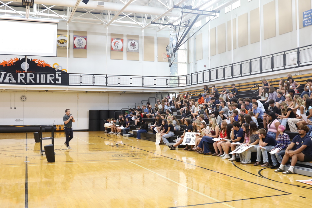 Principal speaking to the students on the bleachers