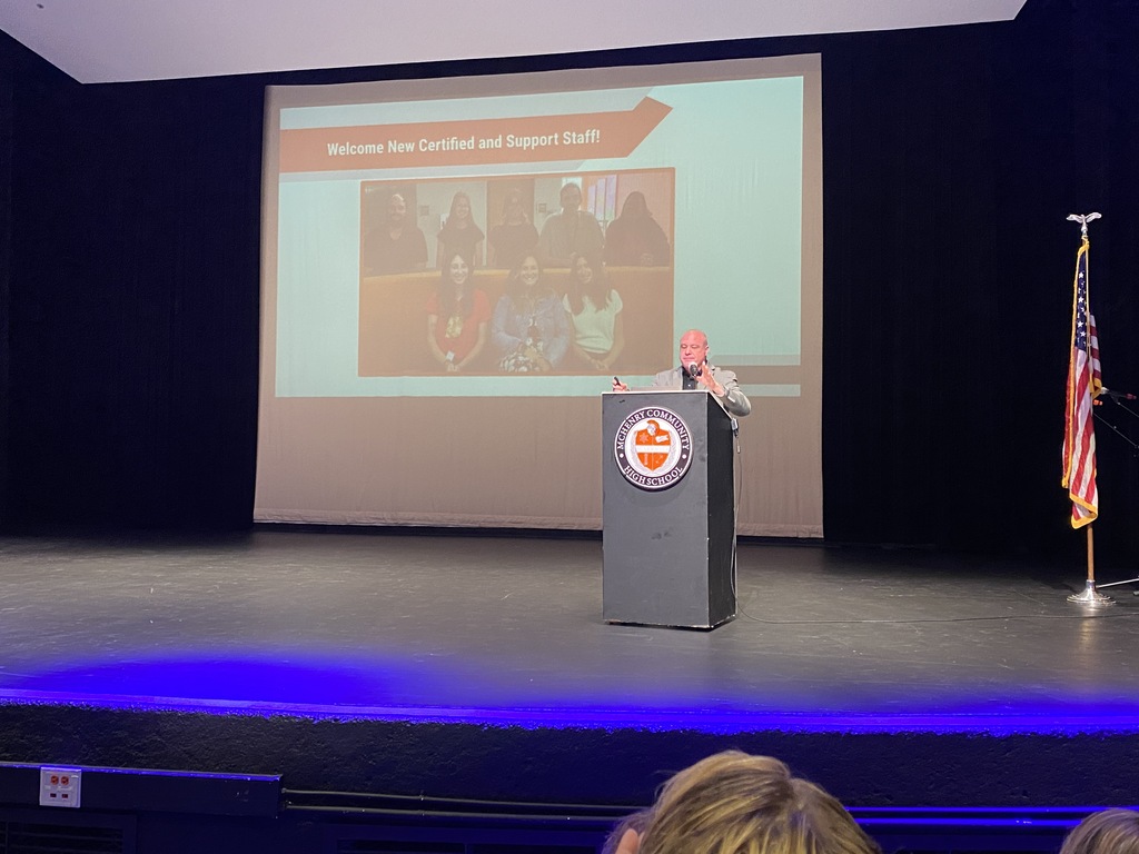 Dr. McTague on stage in front of a slide of new staff 