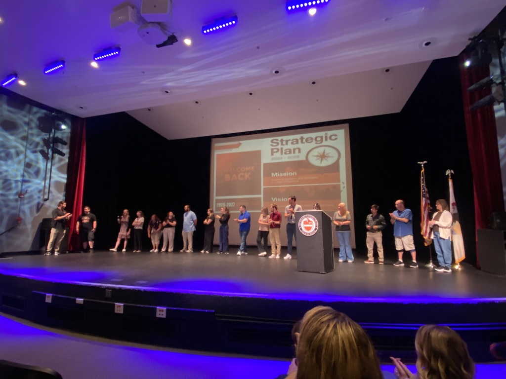 New staff on stage in front of strategic plan slide