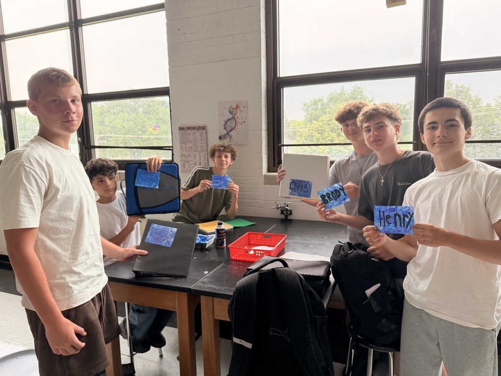 Students holding blue cards with their names at a lab table