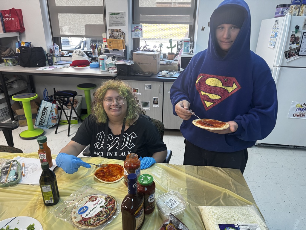 Two students holding pizzas