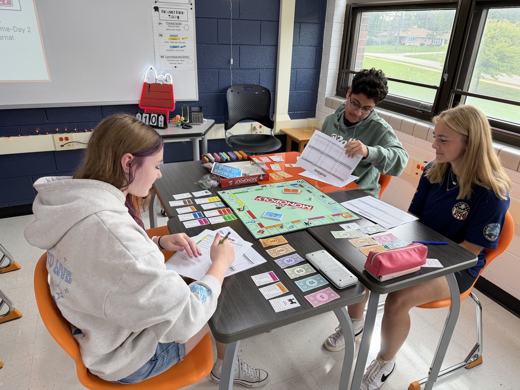 Students playing Monopoly with worksheets