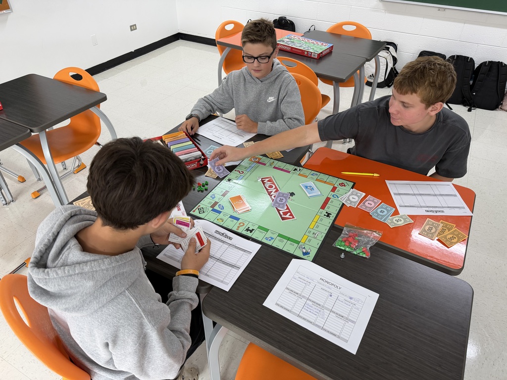 Students playing Monopoly with worksheets