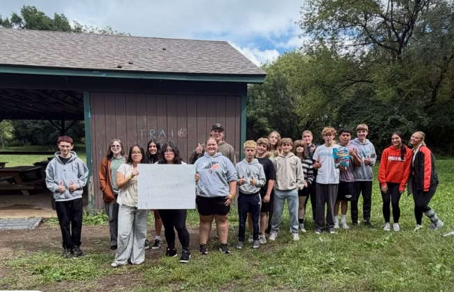 Student AIM group posing at camp and holding a sign