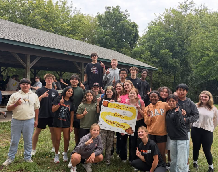 Student AIM group posing at camp and holding a sign