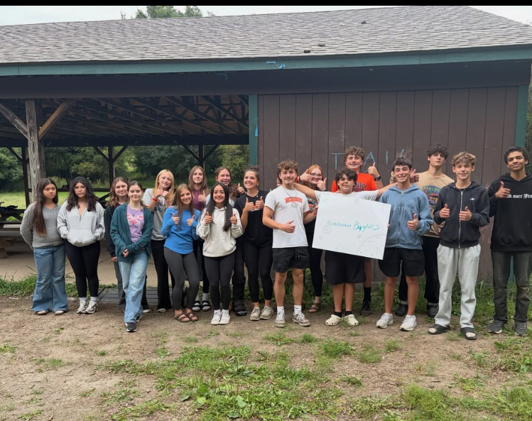 Student AIM group posing at camp and holding a sign