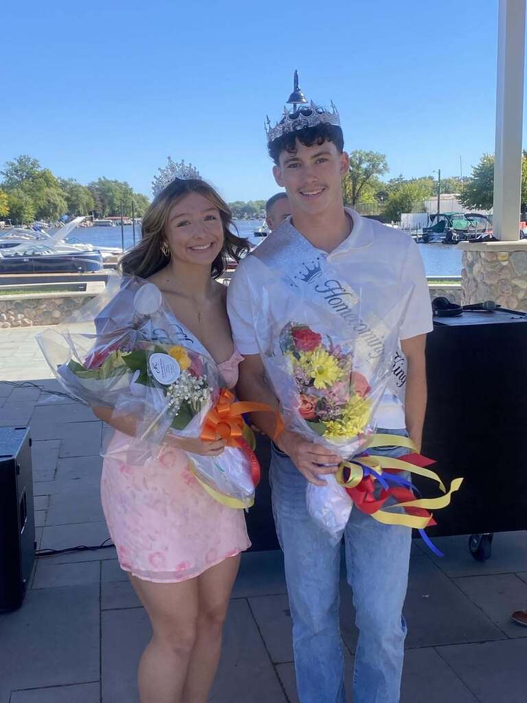 Homecoming king and queen with sashes crowns and holding flowers