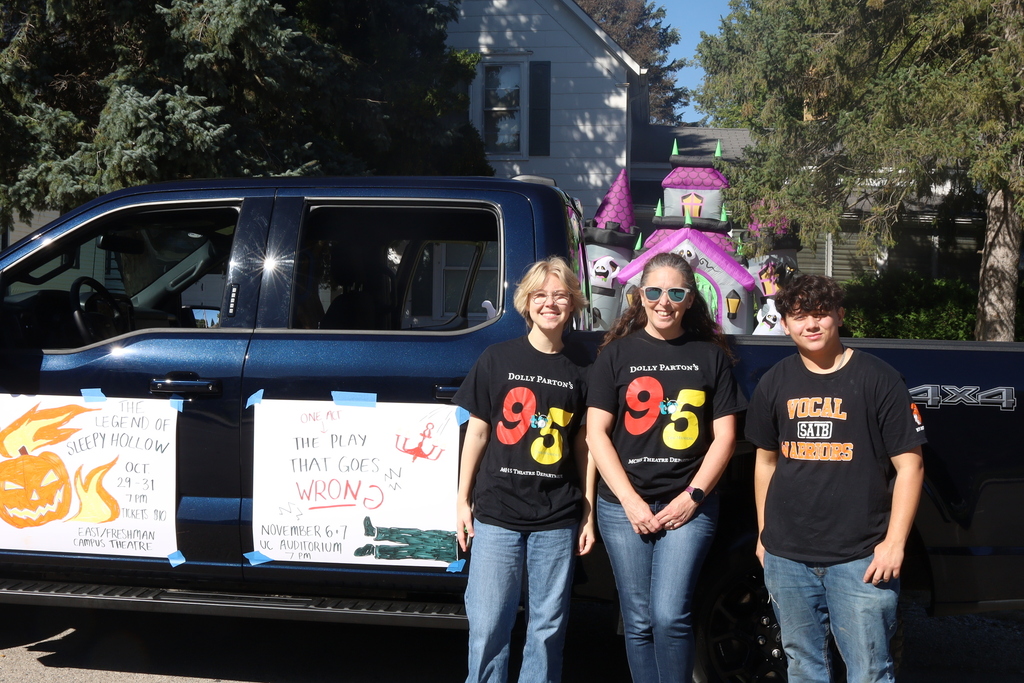 Drama club with homecoming car. Poster on car that says the legen of sleepy hallow october 29-21 and the play that goes wrong november 6-7
