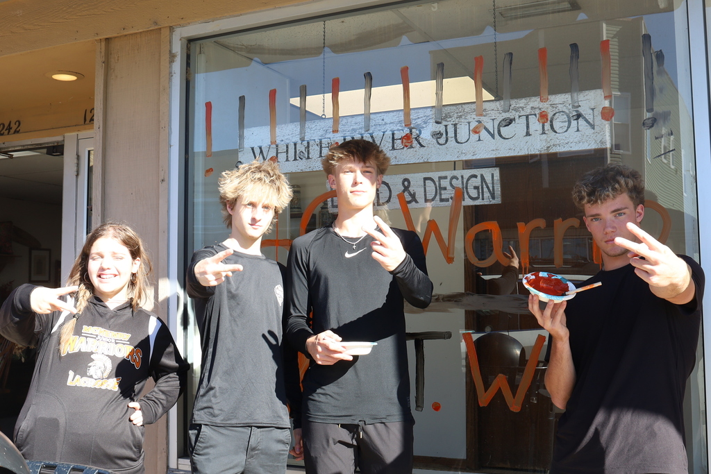 Students holding up peace signs in front of decorated window