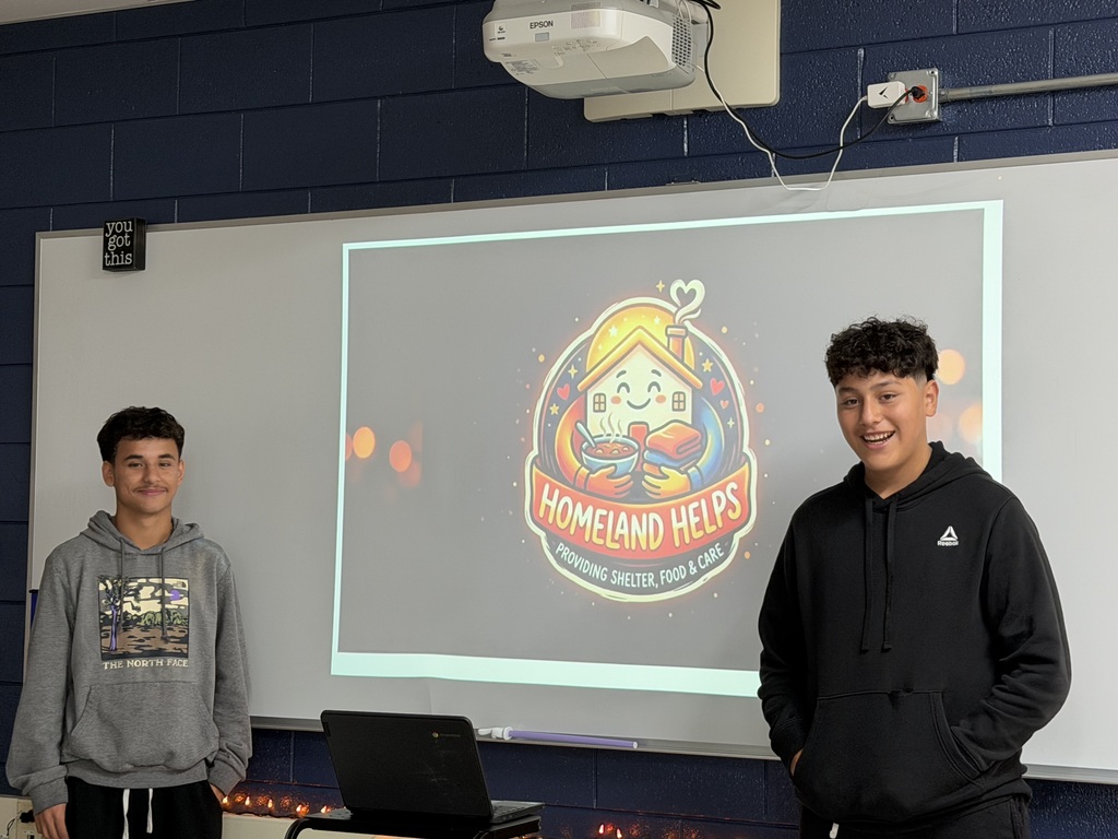 Two students in front of slide that says Homeland helps providing shelter food and care