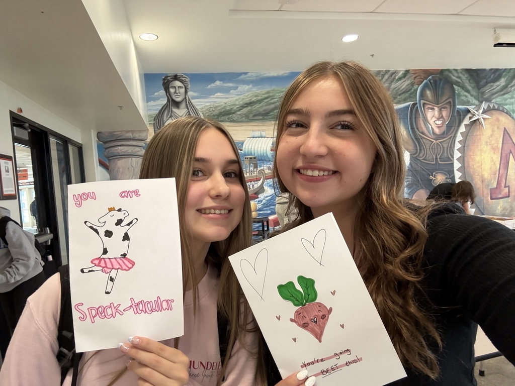 Students holding signs with a card with a cow in a tutu that says you are speck-tacular and another one that with a beet that says "you're going to beet this"
