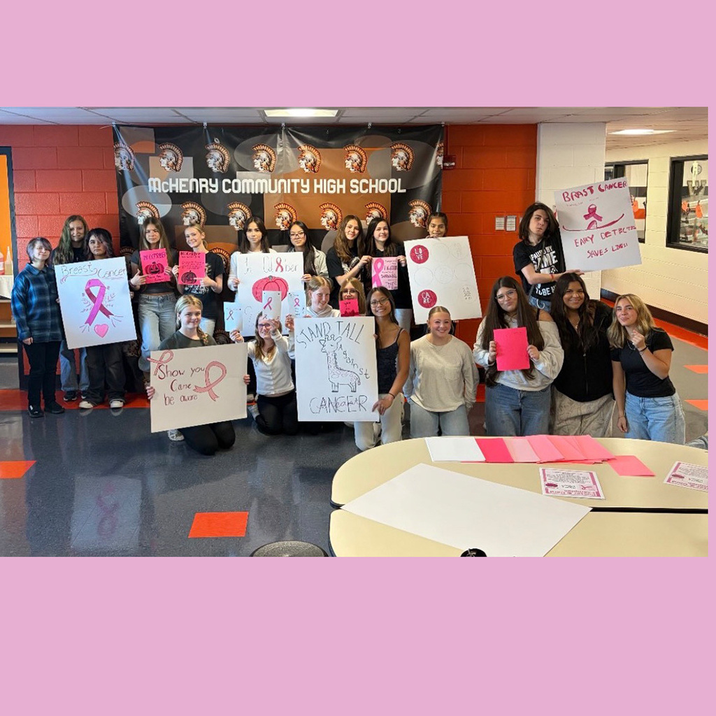 Group of freshen holding various breast cancer support signs: stand tall against cancer with a giraffe, show your care. be aware. Early detection saves lives