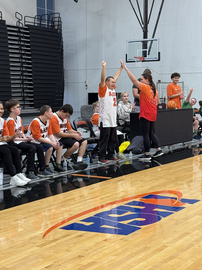 Student on the sidelines holding his hands up cheering, and the coach hiving him