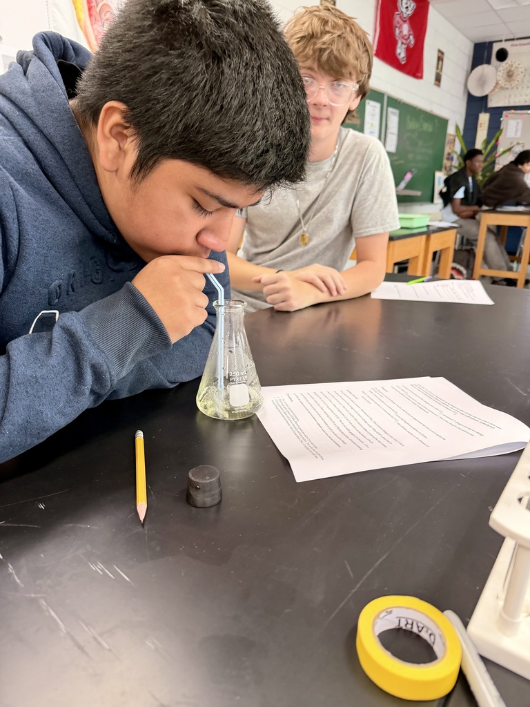 Student exhaling through a straw into a beaker