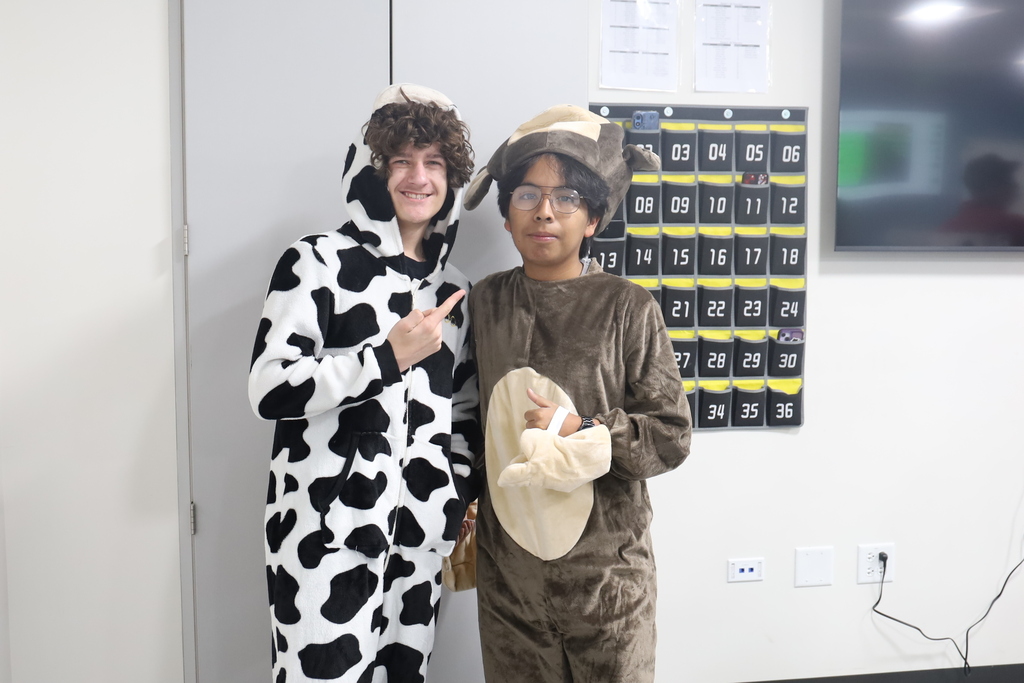 Two students in onesies, cow and monkey.