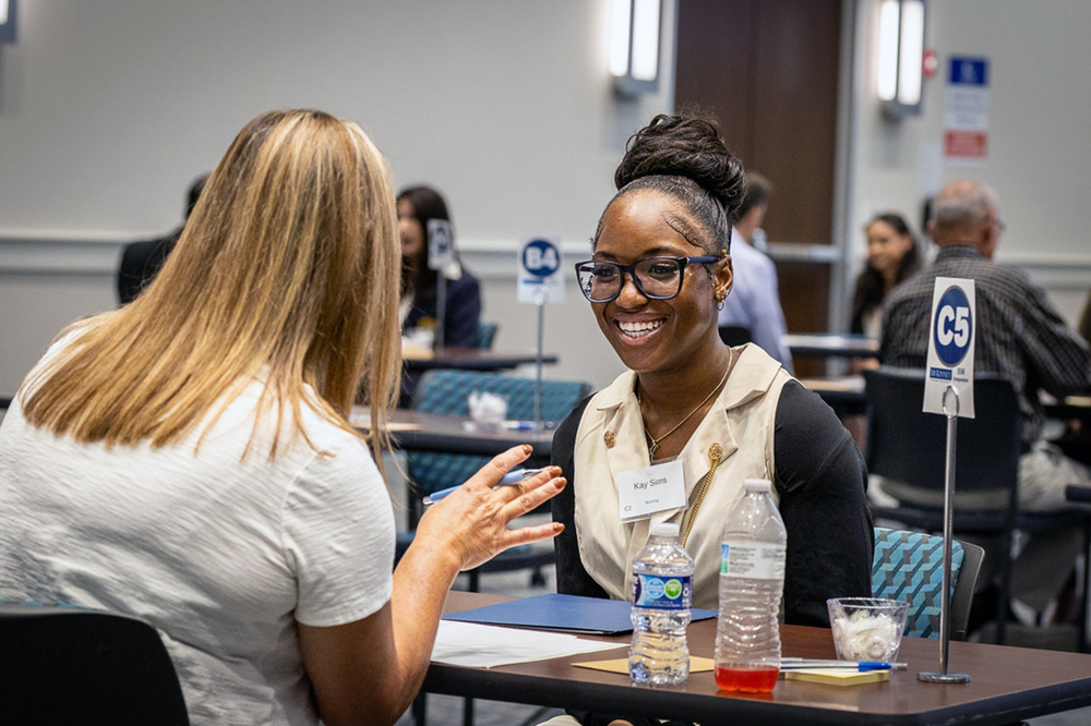 student and interviewer seated at table and student is smiling at interviewer