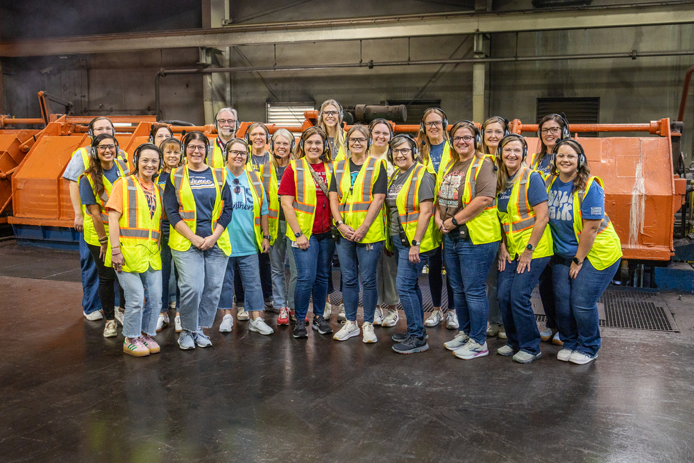 group posing in front of large industrial equipment