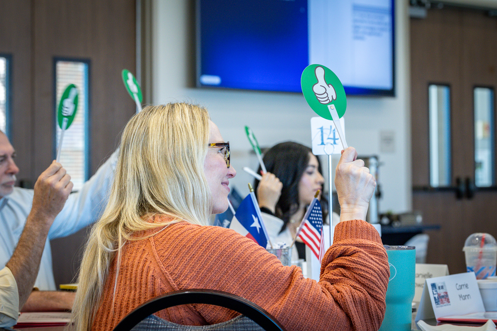 woman at table holding up green thumbs up sign