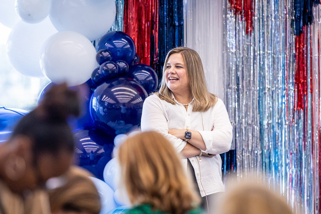 presenter Kristin Poage at the front of the room smiling with arms crossed