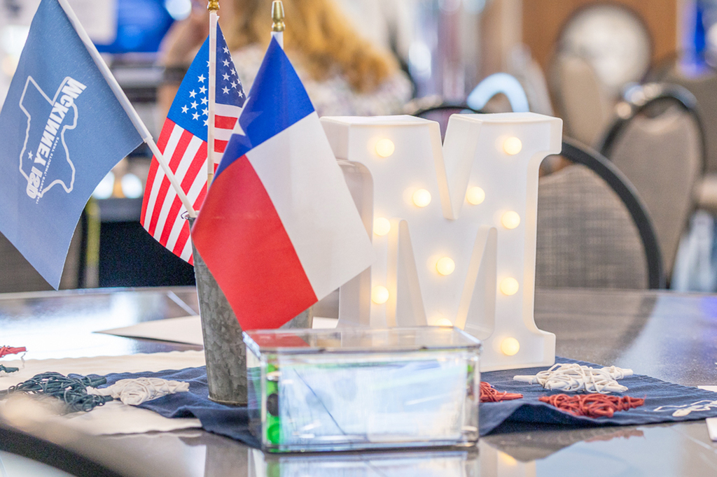 decorations on table that include a lighted M , and three small flags - US flag, Texas flag and McKinney ISD flag