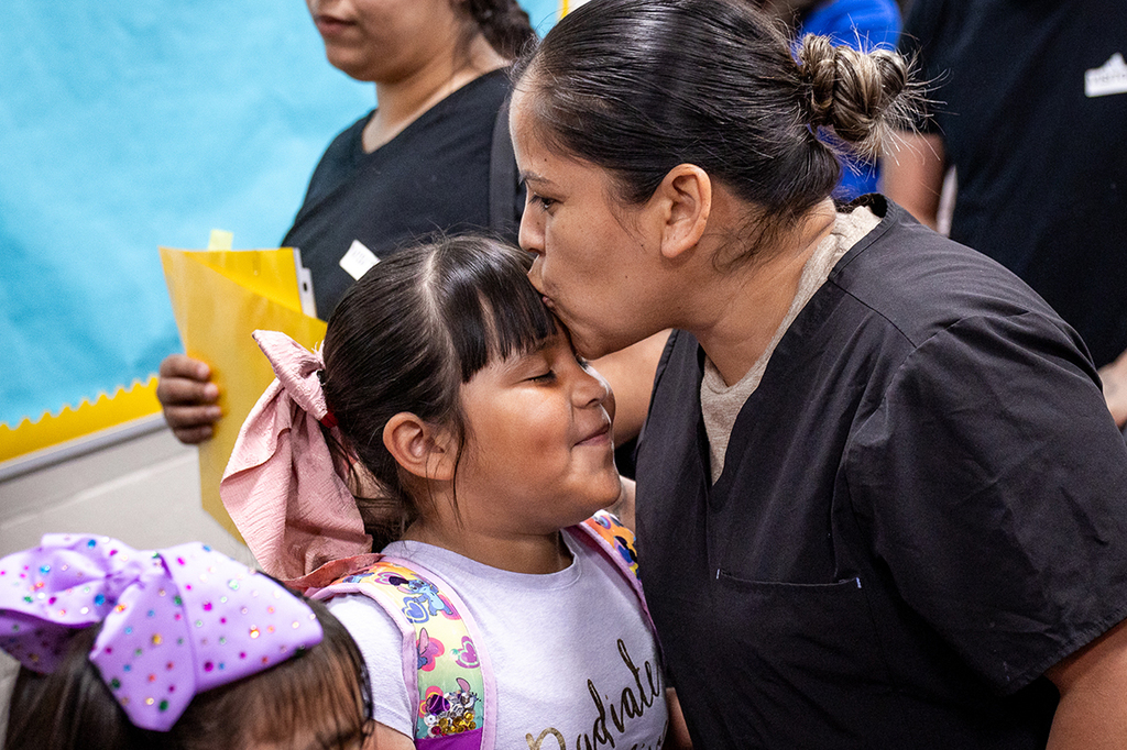 mother kissing her daughter on the head
