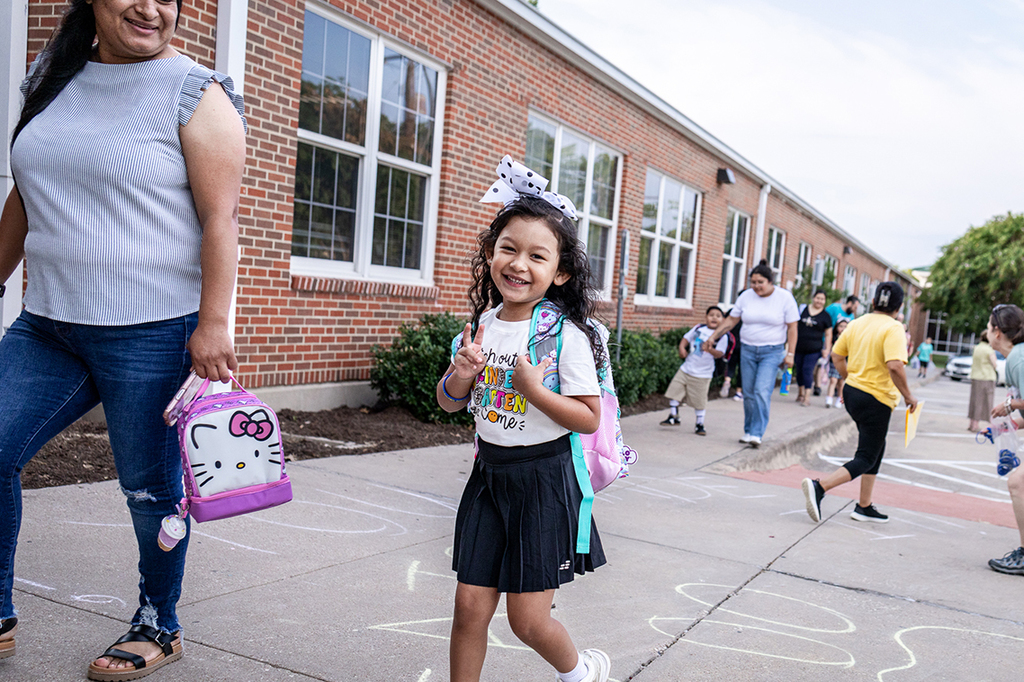 young girl at Caldwell giving peace sign and smiling as she walks up to Caldwell