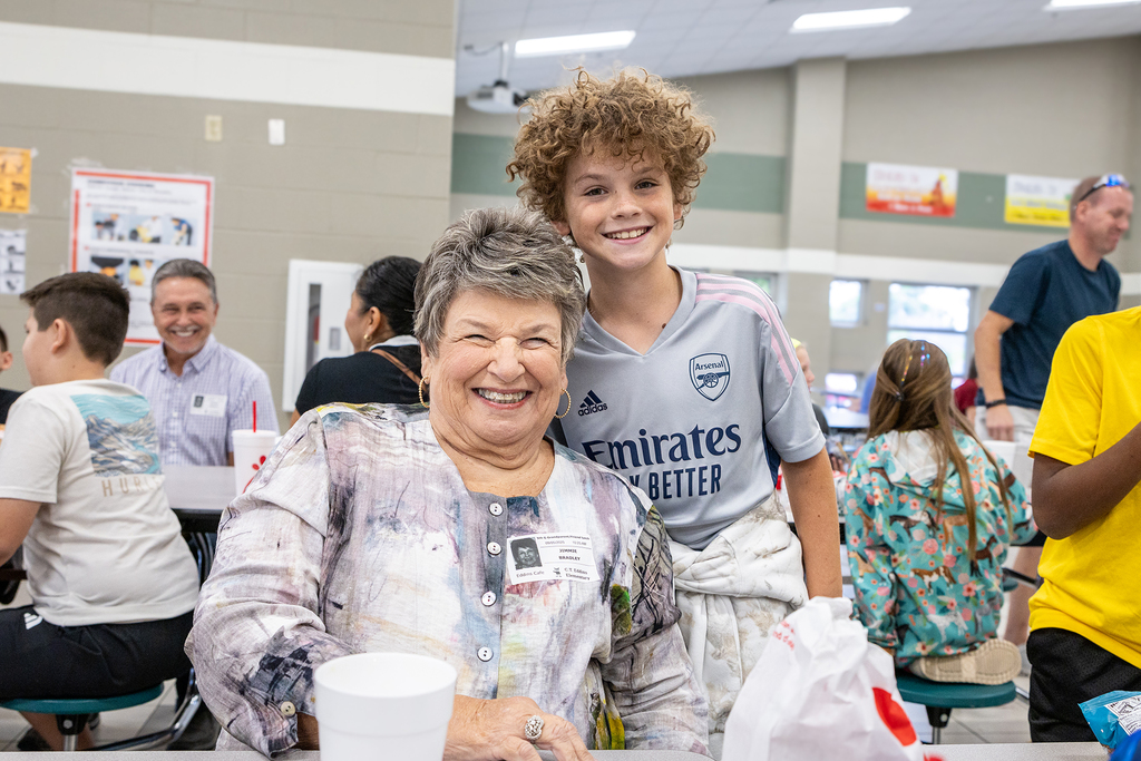 grandson standing behind grandmother and leaning in for photo