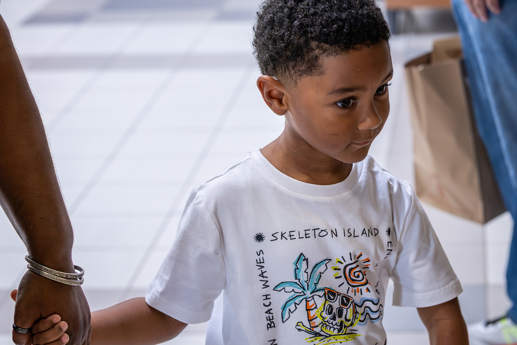 young boy holding the hand of his grandmother as they walk into the cafeteria