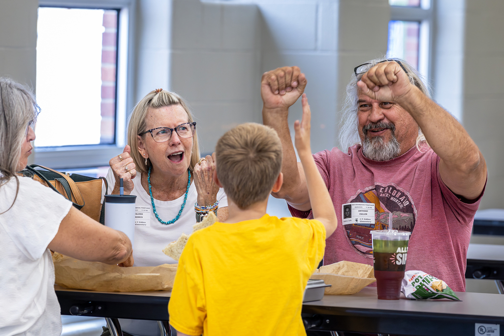 grandfather and grandmother react to something grandson said with smiles and looks of surprise