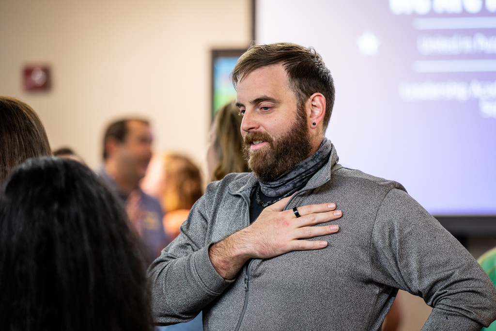 male participant talking with his hand over his chest