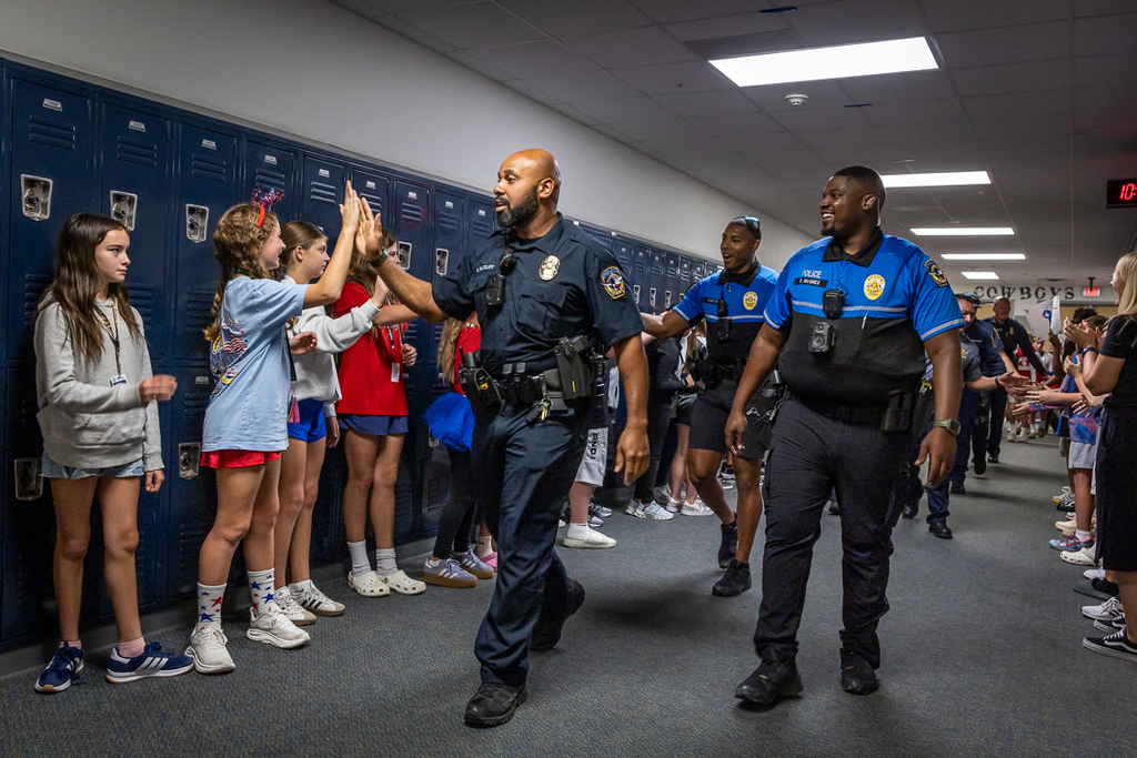 students in hallway cheering and high fiving police officers 