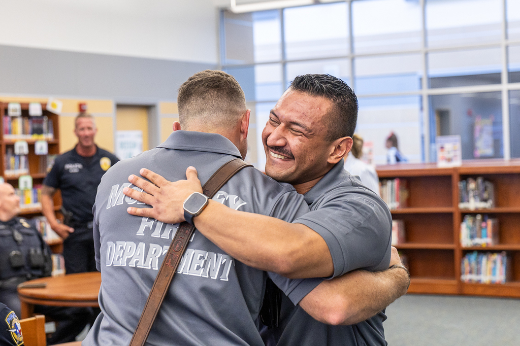 two firefighters smiling and embracing as they greet one another at Cockrill