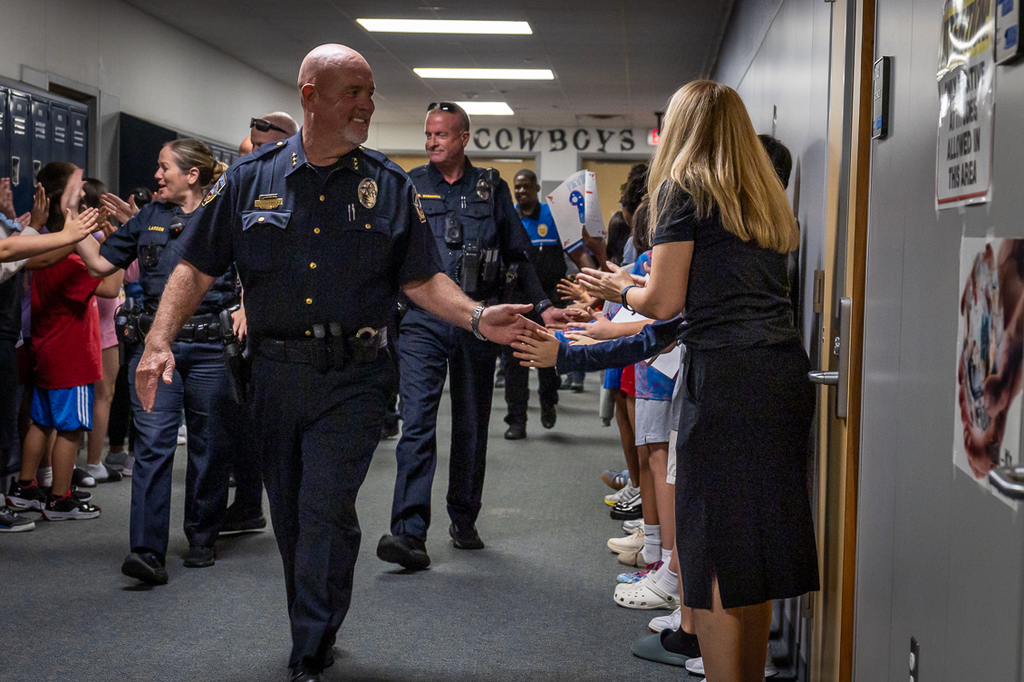 police chief and other officers high fiving students as they move through the halls during the Cockrill Patriot Day parade